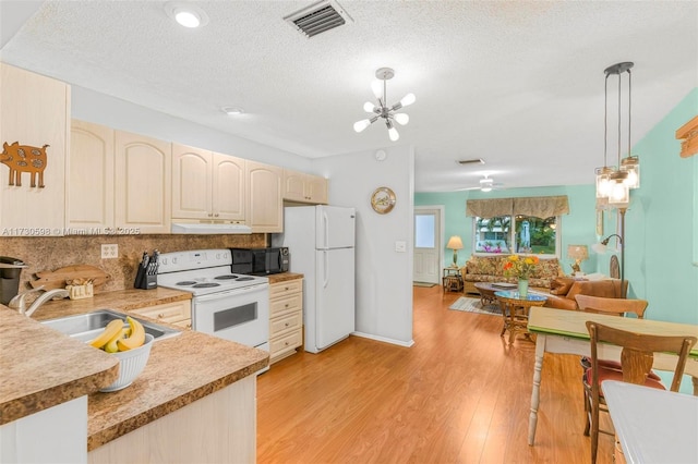 kitchen featuring white appliances, a textured ceiling, sink, decorative light fixtures, and light wood-type flooring