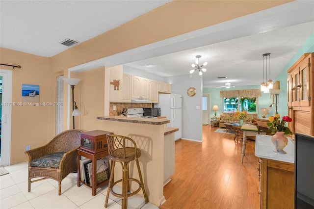 kitchen featuring white appliances, decorative backsplash, hanging light fixtures, kitchen peninsula, and a notable chandelier