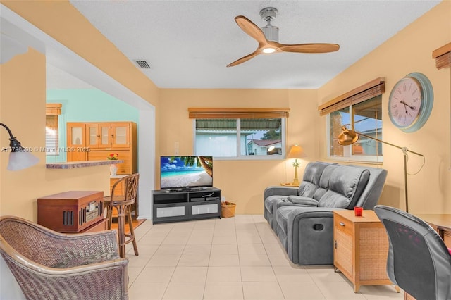 tiled living room with ceiling fan and a textured ceiling