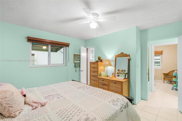 bedroom featuring ceiling fan, a textured ceiling, and light tile patterned floors