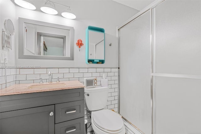 bathroom with toilet, tasteful backsplash, a shower with shower door, and vanity