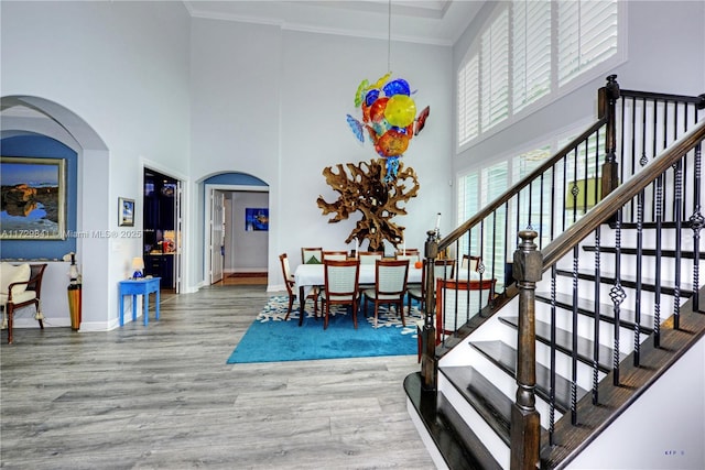 dining area with crown molding, hardwood / wood-style flooring, and a towering ceiling