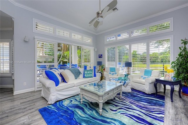 living room with ceiling fan, plenty of natural light, wood-type flooring, and ornamental molding