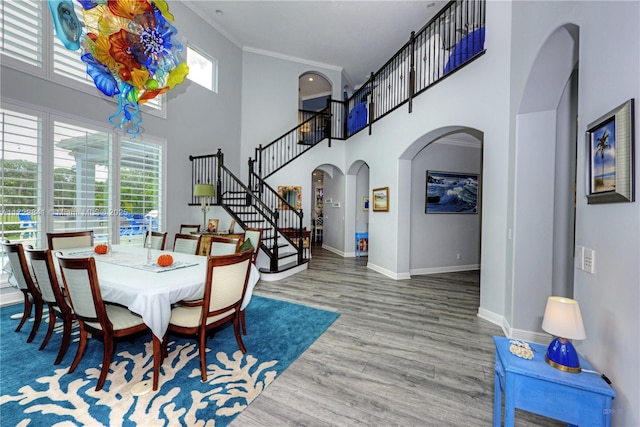 dining space with a high ceiling, hardwood / wood-style floors, and crown molding