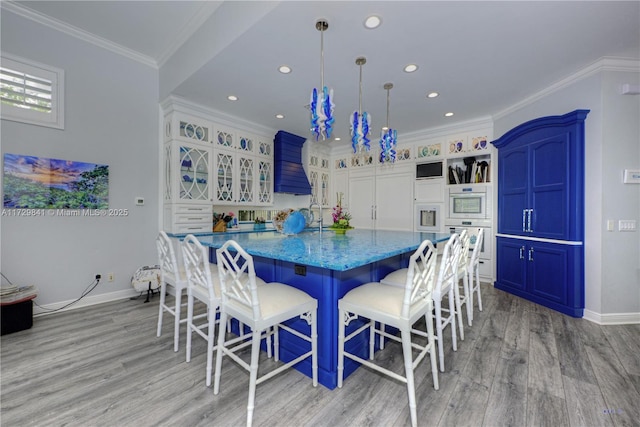 dining room with light hardwood / wood-style floors, sink, and ornamental molding