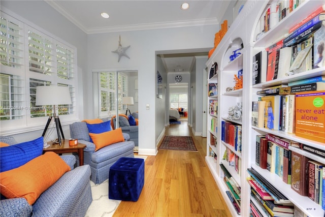 sitting room with ornamental molding and light hardwood / wood-style flooring