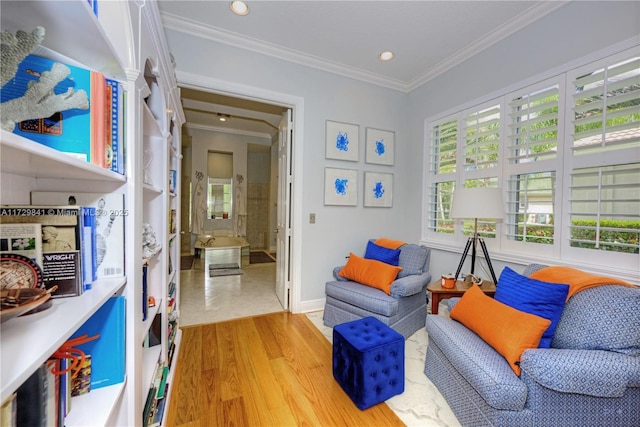 sitting room with light wood-type flooring and ornamental molding