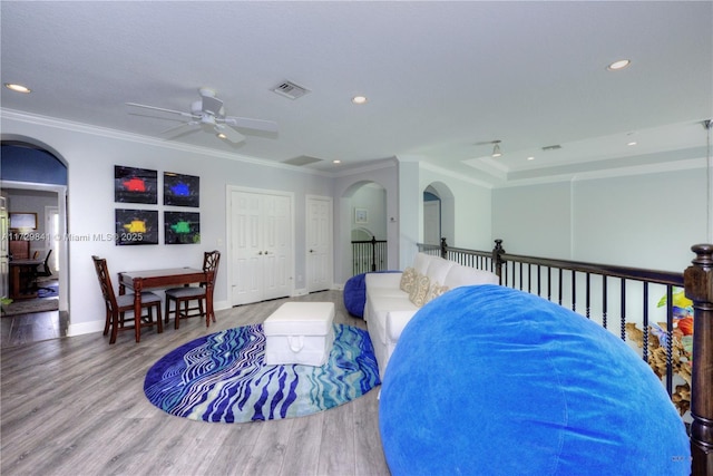 living room with ceiling fan, wood-type flooring, and ornamental molding