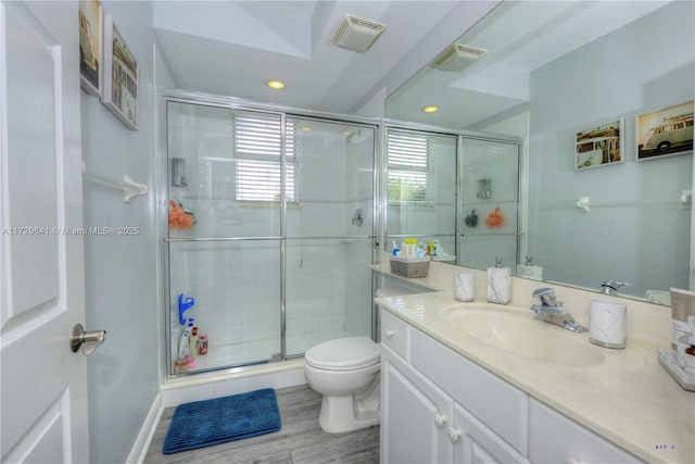 bathroom featuring vanity, toilet, and a shower with shower door