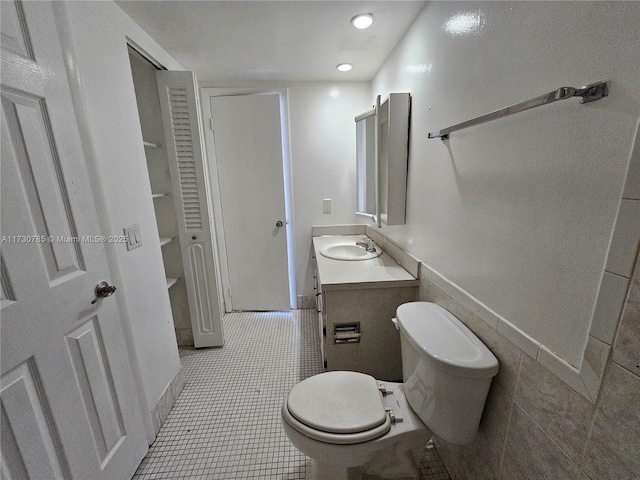 bathroom featuring tile patterned floors, toilet, tile walls, and vanity