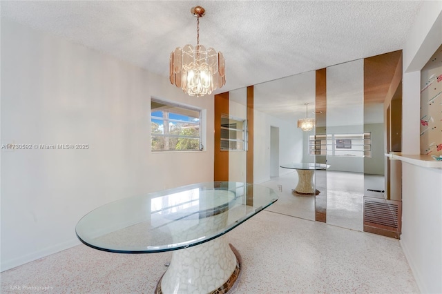 dining space featuring a textured ceiling and a chandelier