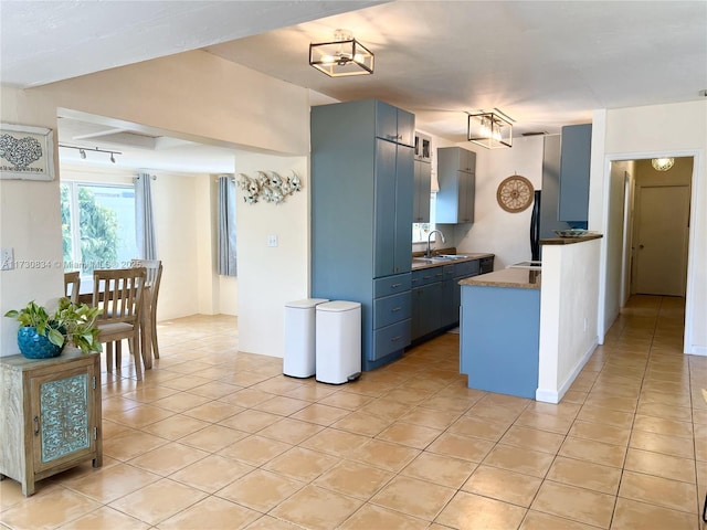 kitchen featuring blue cabinetry, sink, and light tile patterned floors