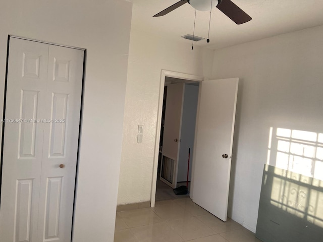 unfurnished bedroom with a closet, ceiling fan, and light tile patterned floors