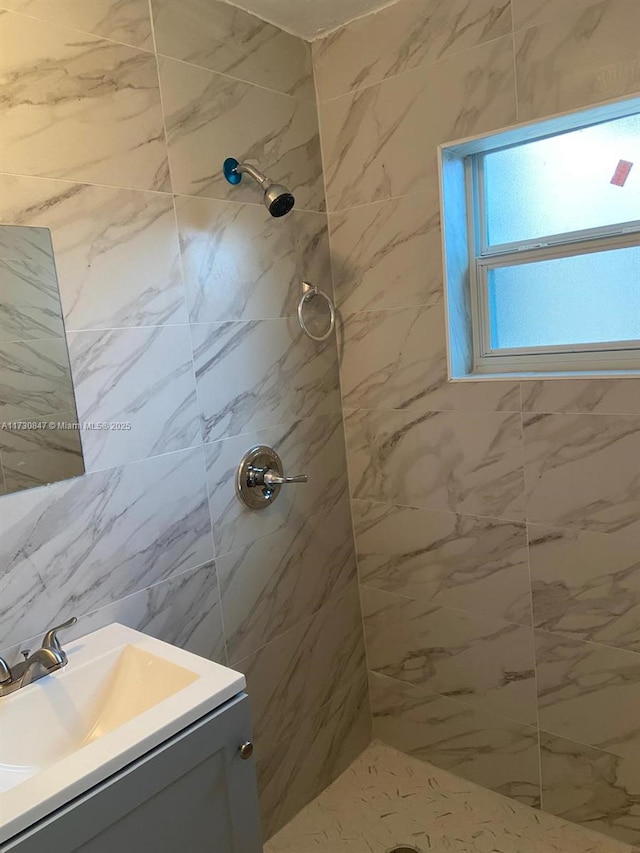 bathroom with tiled shower and vanity