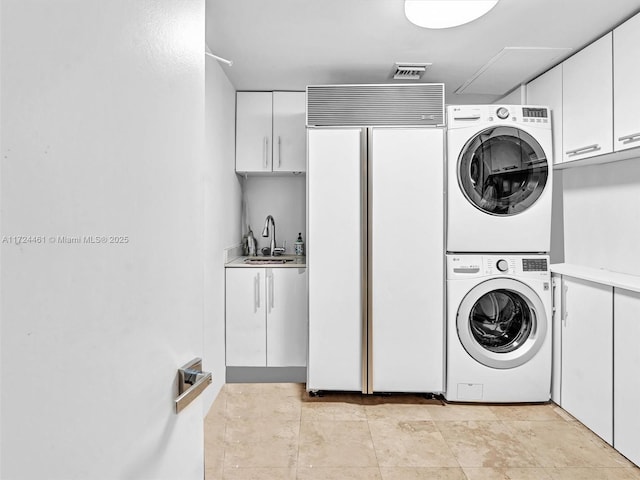 laundry room featuring sink, stacked washing maching and dryer, and cabinets