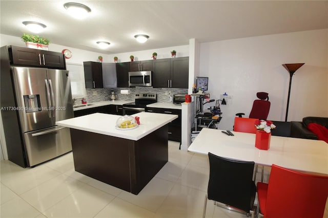 kitchen featuring sink, a center island, light tile patterned floors, appliances with stainless steel finishes, and decorative backsplash