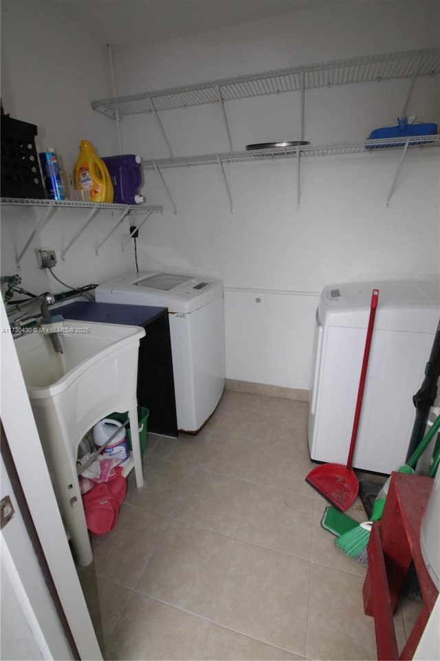 laundry area with light tile patterned flooring, separate washer and dryer, and sink