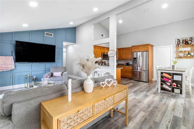 living room with light hardwood / wood-style flooring and high vaulted ceiling