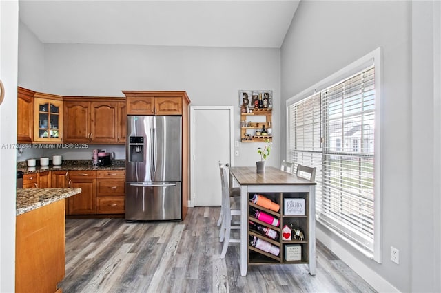 kitchen with dark stone countertops, hardwood / wood-style flooring, and stainless steel fridge