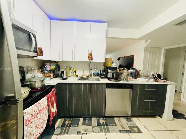 kitchen featuring sink, white cabinets, light tile patterned floors, and stainless steel appliances