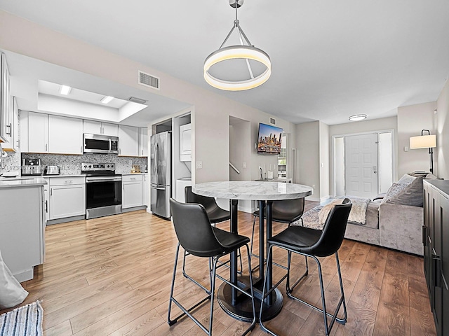 dining space with light hardwood / wood-style floors and a raised ceiling