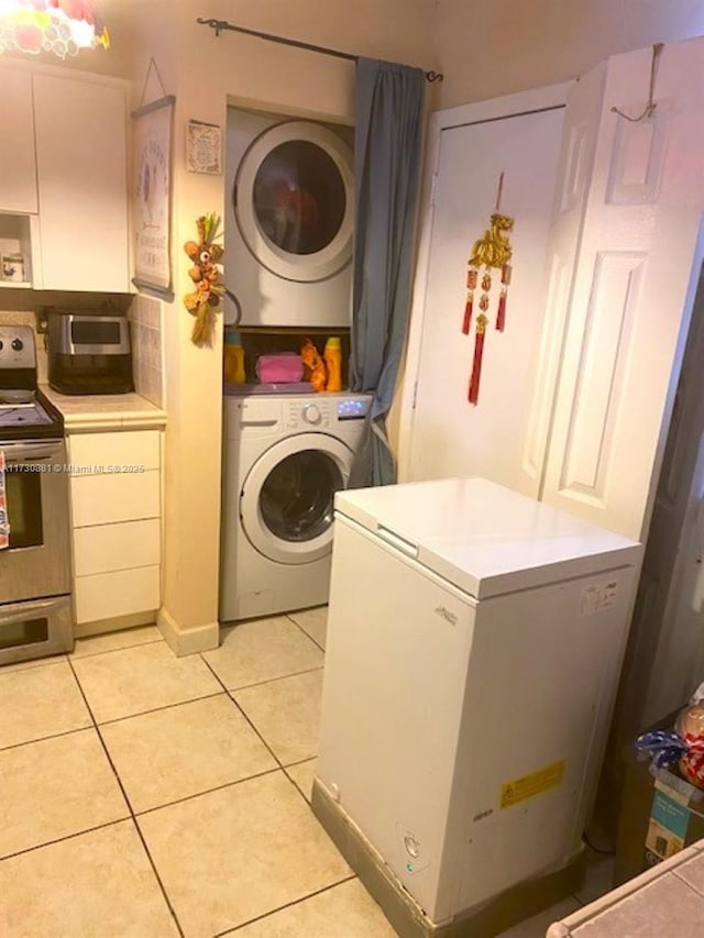 laundry area featuring stacked washer and clothes dryer and light tile patterned floors