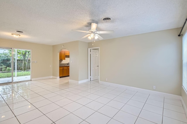 tiled empty room with a textured ceiling and ceiling fan