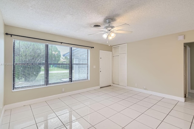 unfurnished room featuring ceiling fan, light tile patterned floors, and a textured ceiling