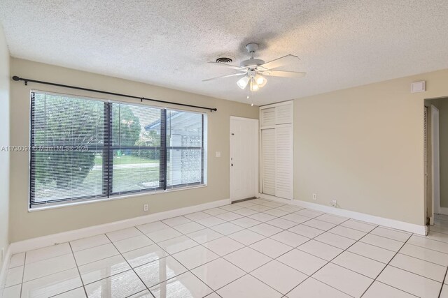 unfurnished room featuring ceiling fan, light tile patterned floors, and a textured ceiling