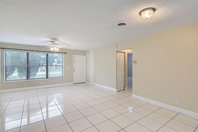 tiled empty room with ceiling fan and a textured ceiling