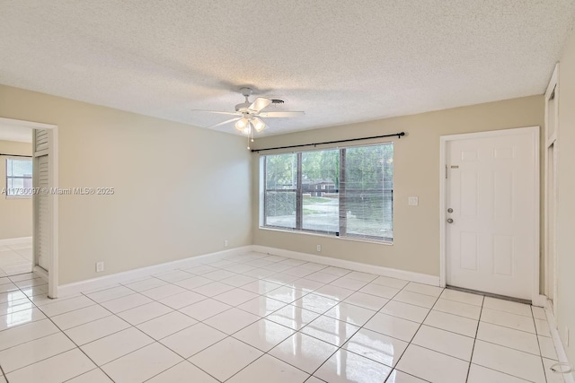 tiled spare room with a textured ceiling and ceiling fan