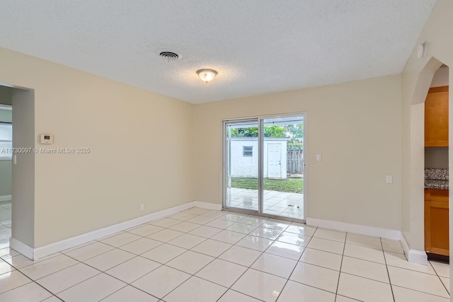 spare room featuring light tile patterned flooring and a textured ceiling