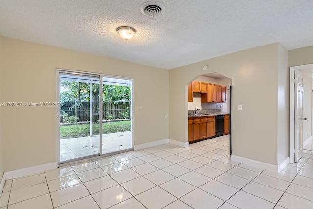 unfurnished living room with sink, a textured ceiling, and light tile patterned floors