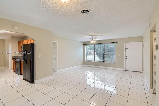 unfurnished living room featuring ceiling fan, light tile patterned floors, and a textured ceiling