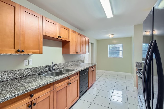 kitchen with sink, black appliances, light tile patterned floors, and dark stone countertops