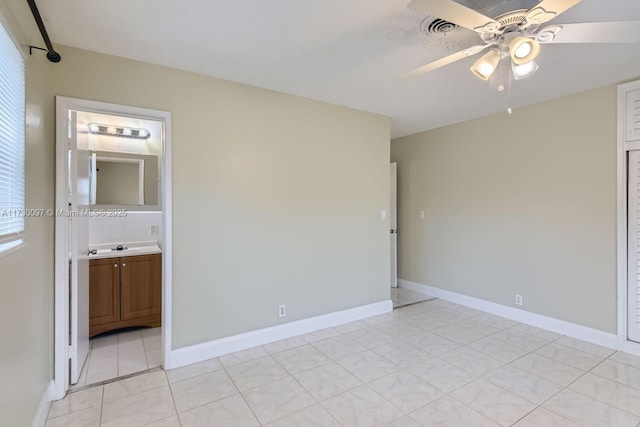 unfurnished bedroom with light tile patterned floors, ensuite bath, and ceiling fan