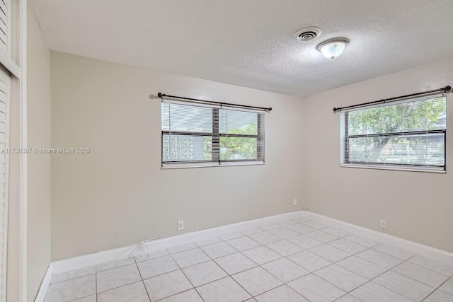 tiled empty room featuring plenty of natural light and a textured ceiling