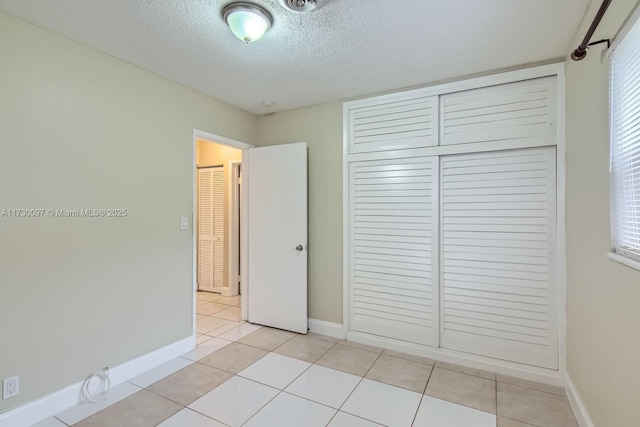 unfurnished bedroom with a textured ceiling, a closet, and light tile patterned flooring