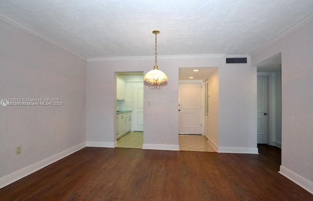 spare room with crown molding, hardwood / wood-style flooring, a textured ceiling, and a notable chandelier