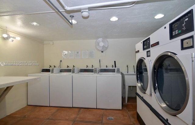 laundry area featuring dark tile patterned flooring, a textured ceiling, and washing machine and dryer