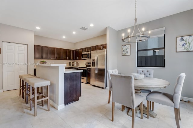 kitchen featuring pendant lighting, appliances with stainless steel finishes, a center island, dark brown cabinets, and a breakfast bar area