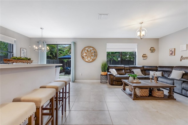 living room with a notable chandelier, light tile patterned floors, and plenty of natural light