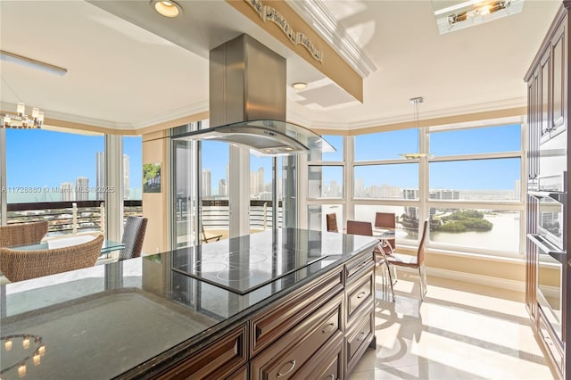 kitchen with crown molding, dark brown cabinets, island range hood, black electric cooktop, and dark stone counters