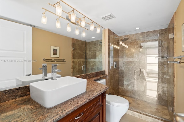 bathroom with a shower with door, vanity, and toilet