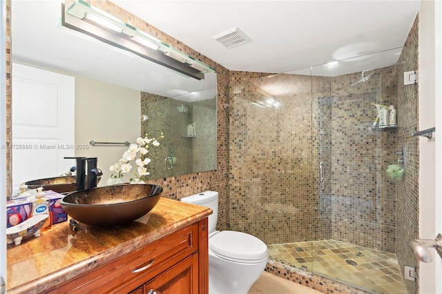 bathroom with vanity, a shower with shower door, tile walls, and toilet