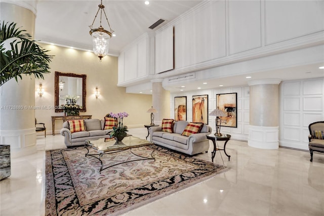 living room featuring decorative columns, crown molding, a high ceiling, and a chandelier