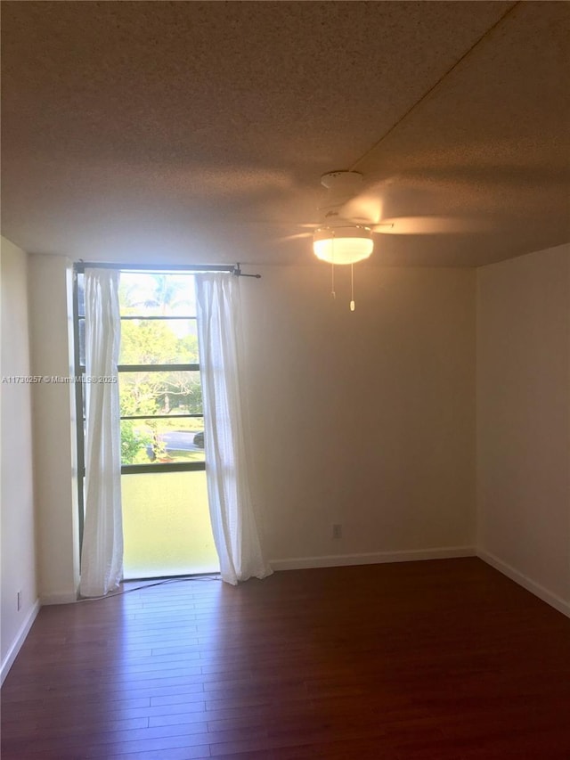 empty room featuring ceiling fan, a textured ceiling, and dark hardwood / wood-style floors