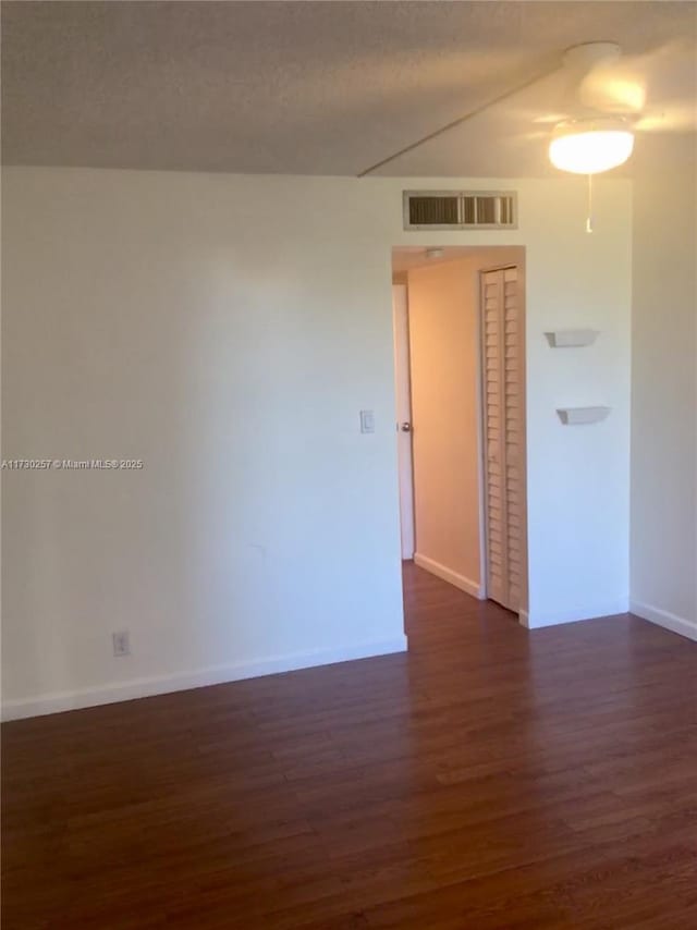 unfurnished room featuring dark hardwood / wood-style floors and a textured ceiling