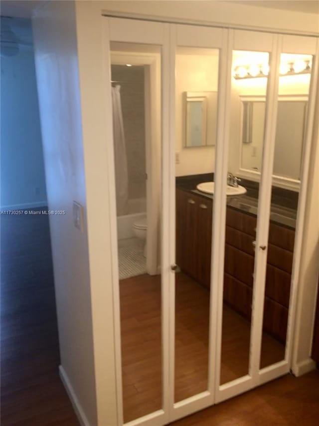 interior space featuring vanity, toilet, shower / bath combination with curtain, and wood-type flooring