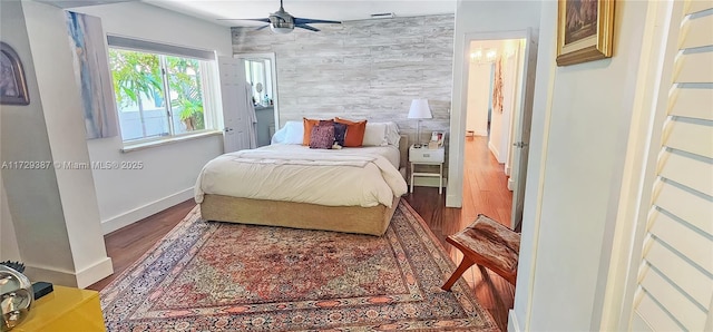 bedroom with hardwood / wood-style flooring, wooden walls, and ceiling fan